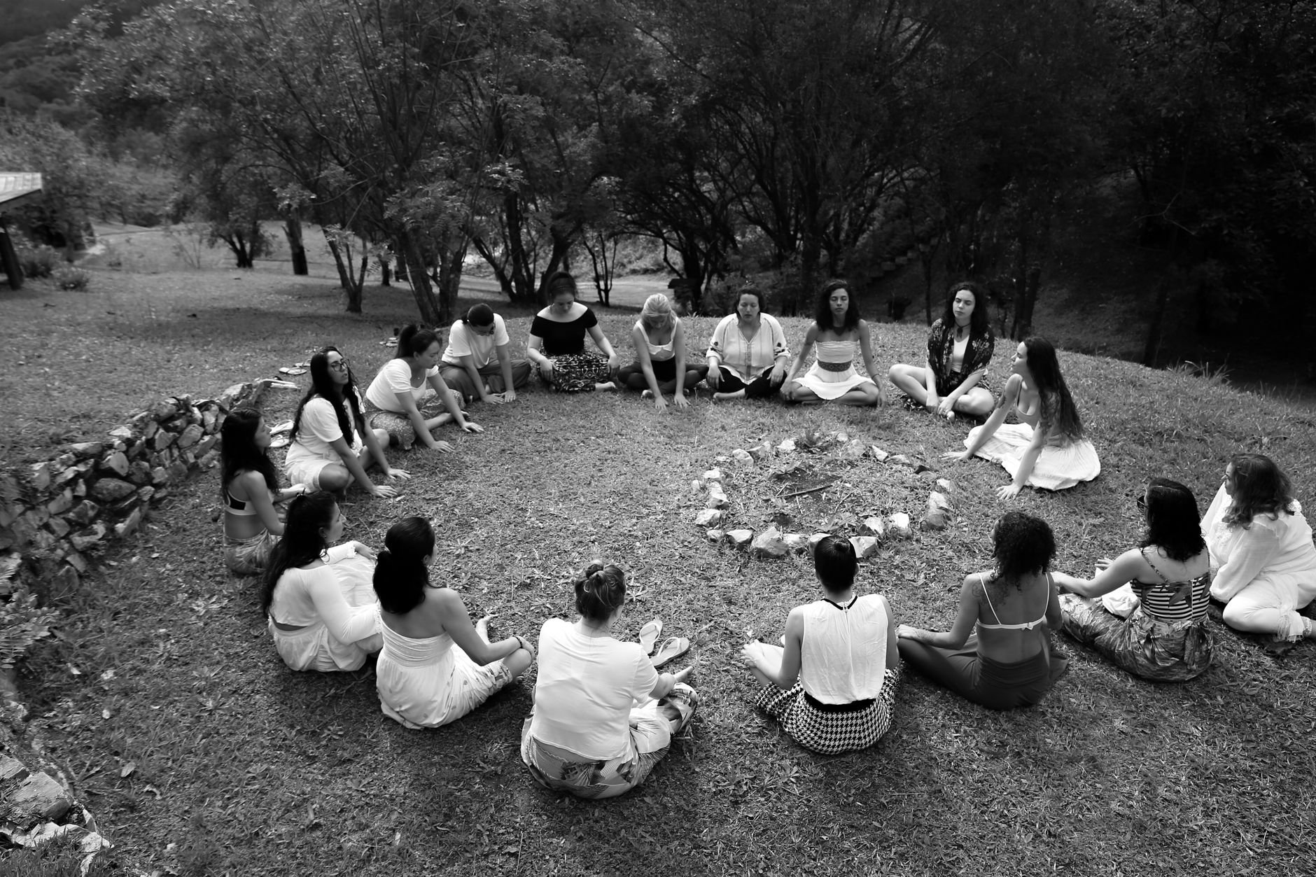 A group of diverse women sitting in a circle together in an outdoor community setting.