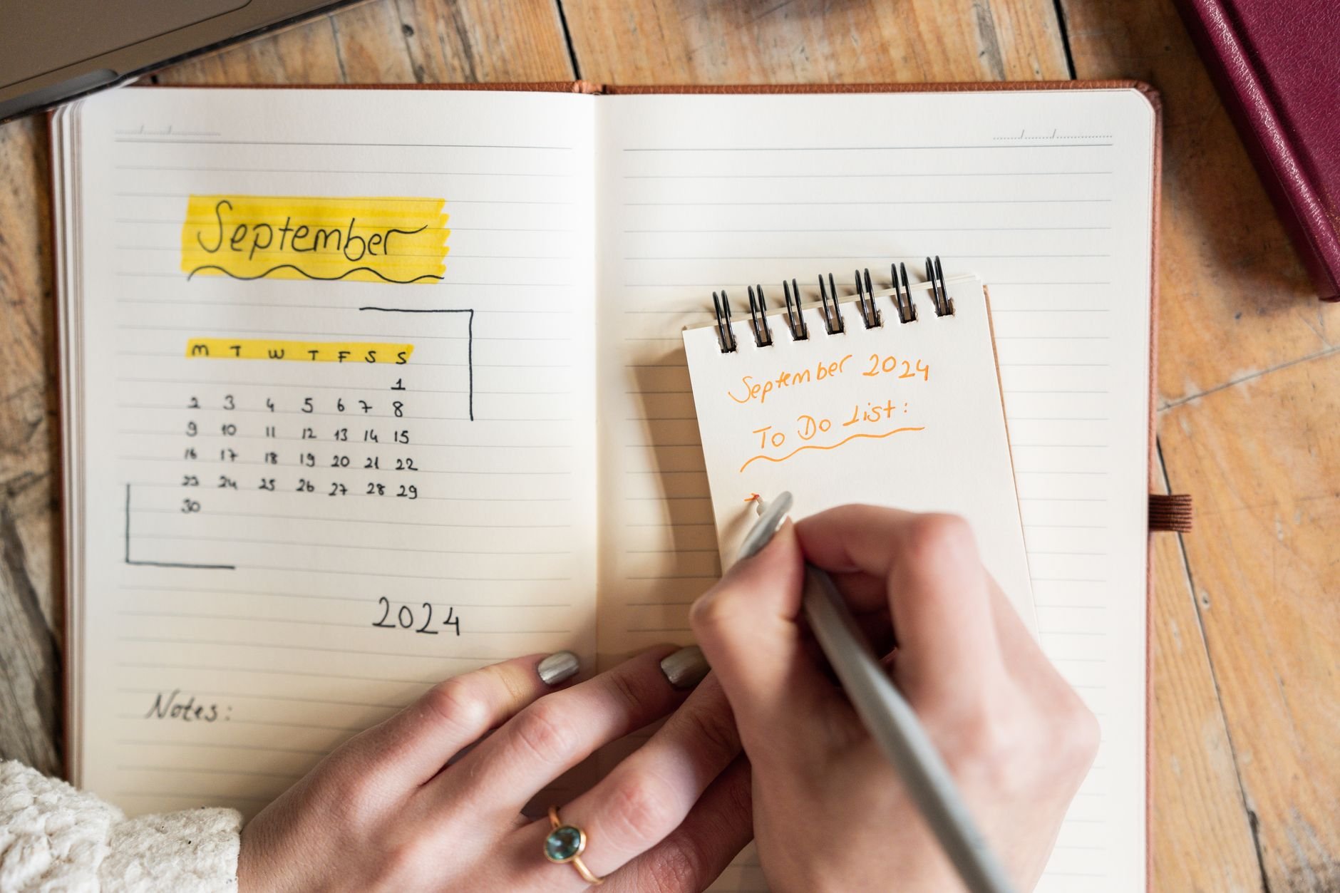 Close-up of a woman writing thoughtfully in a notebook, planning carefully.