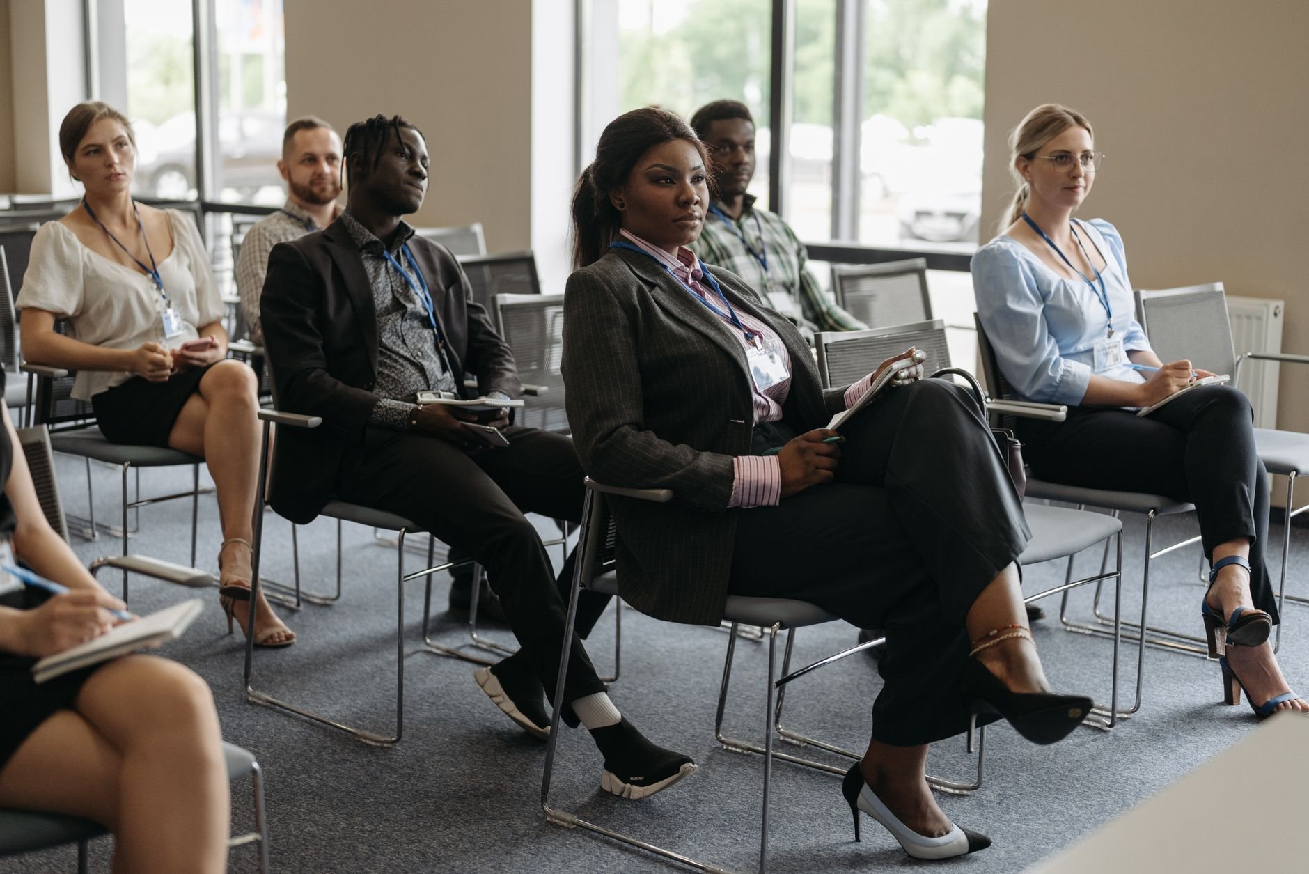 A diverse group of adults attentively listening at a community workshop indoors.